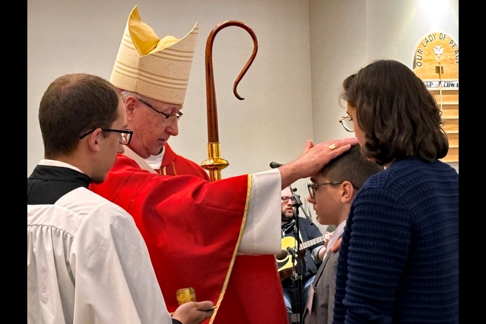 Archbishop Richard W. Smith annoints a young parish member of Innisfail's Our Lady of Peace Catholic Church on June 8 during the Celebration of the Sacrament of Confirmation. Johnnie Bachusky/MVP Staff