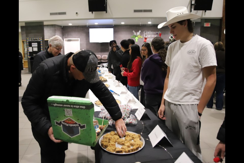 Nate Reist, right, watches as Ken Taylor chooses a treat during Christmas Palooza.
Doug Collie/MVP Staff