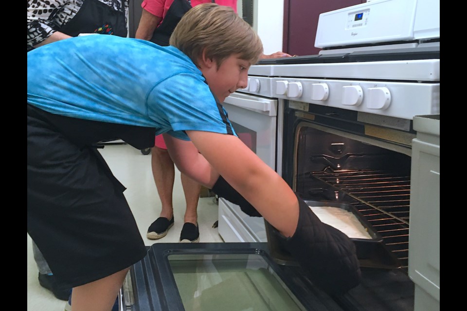 Declan Free, 12, puts into the oven at the Royal Canadian Legion Sundre Branch #223 kitchen a Moussaka – a Greek dish akin to a green lasagna with layers of cheese and traditionally egg plant but in this instance zucchini – on Wednesday, Aug. 17 during a Greenwood Neighbourhood Place Society initiative called Cooking Up Connections. 
Simon Ducatel/MVP Staff 