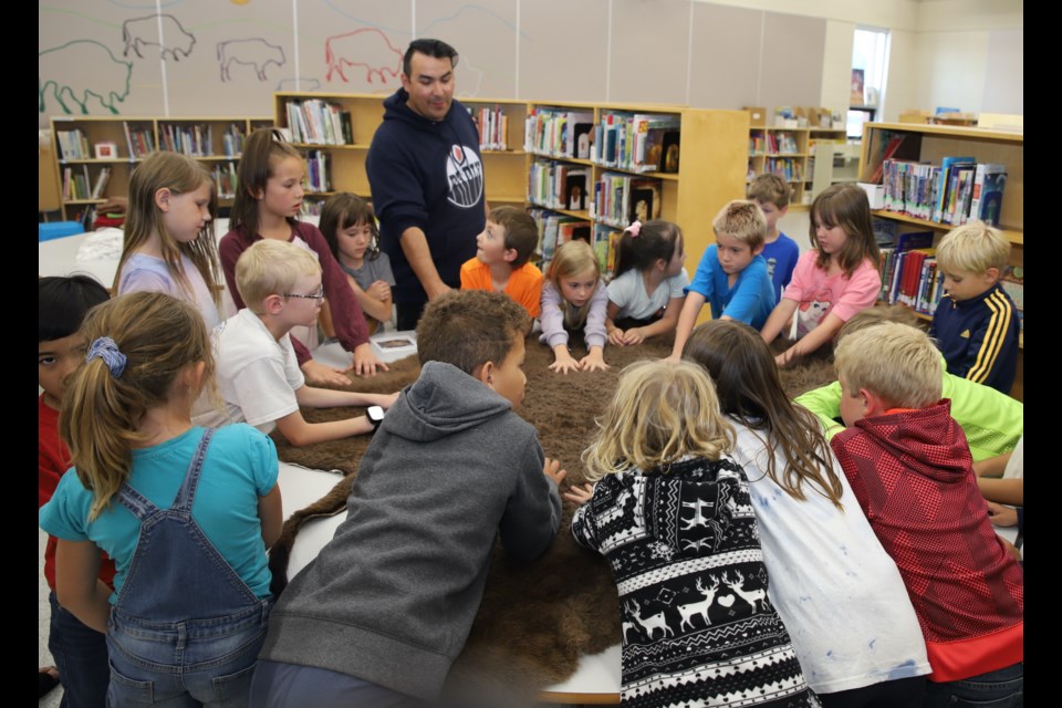 Cree knowledge keeper encourages students to feel a buffalo hide.