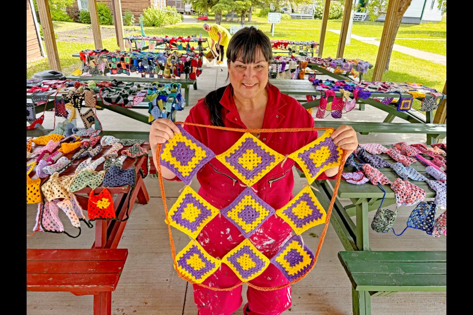 Innisfail artist Karen Scarlett just prior to the start of the installation for the Heritage Quilt Crochet BOMB Project on June 23 at the Innisfail & District Historical Village. Behind her are more than 1,400 granny squares created by more than 100 dedicated crochet enthusiasts to make dozens of quilts for the project. Johnnie Bachusky/MVP Staff