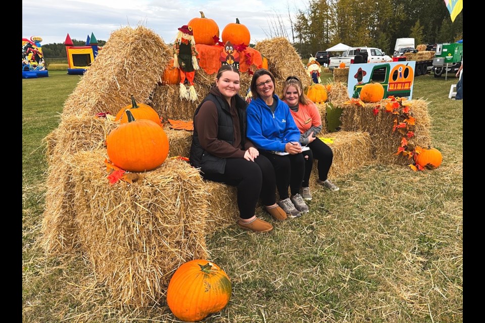 Jamie Bergen, vice-president of the Innisfail Special Events Planning Society (centre), with daughter Ainsley (left) and Mikayla Stott, a volunteer at the Innisfail Fall Festival on Sept. 14 and 15, take a break during the festival's first day. The event attracted at least 3,000 locals and out-of-town visitors. Johnnie Bachusky/MVP Staff