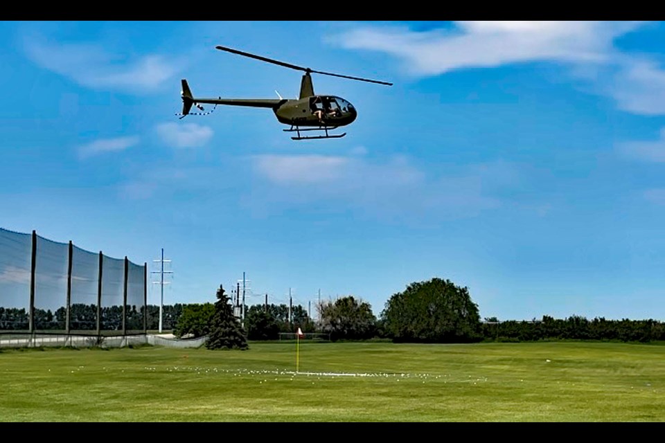 A helicopter, owned and flown by Wade McAllister of Antler Valley Farm, drops 500 golf balls close to the Canada Day flag pin on the driving range of the Innisfail Golf Club. The ball drop on June 29 was part of a fundraiser at the 37th annual Rotary Club of Innisfail Charity Golf Classic. 
Submitted photo