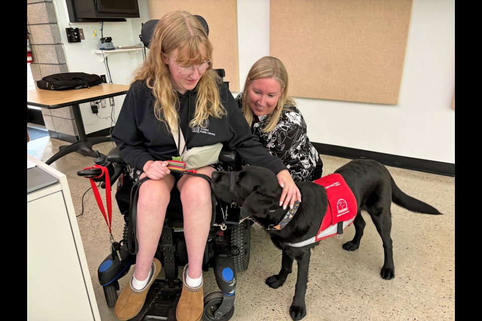 Innisfailian Jeslyn Ramsay, left, and her mother Amy, manager of the Innisfail Public Library, offer love and attention to the teen's task-trained service dog Stanley followng her moving public presentation at the First Annual Summer Program Wrap Up Party on Aug. 15 at the Innisfail Library/Learning Centre. Johnnie Bachusky/MVP Staff