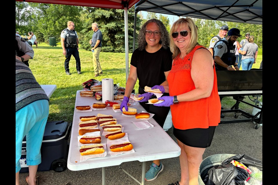 Joy Milne, past chair of the Innisfail's Policing & Safe Community Committee, left, and Rhonda Turnquist, administrative assistant for Innisfail Fire and Protective Services, were busy serving Innisfailians hot dogs at the second annual BBQ in the Park on Aug. 13. Johnnie Bachusky/MVP Staff