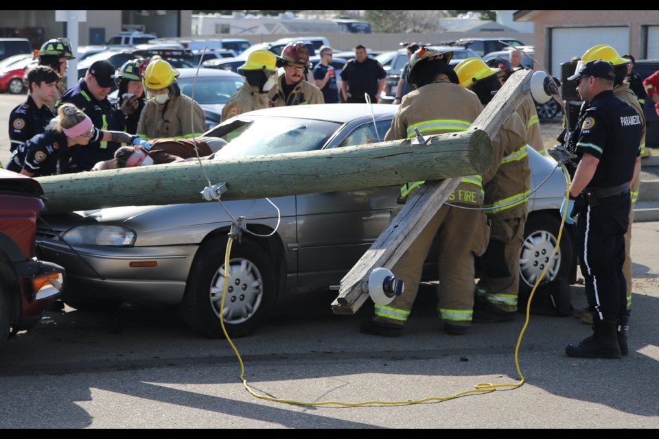 Ambulance staff assess one patient while firefighters work to extract another passenger from the vehicle during the P.A.R.T.Y. mock accident, held May 3 just west of the Olds Fire Hall.