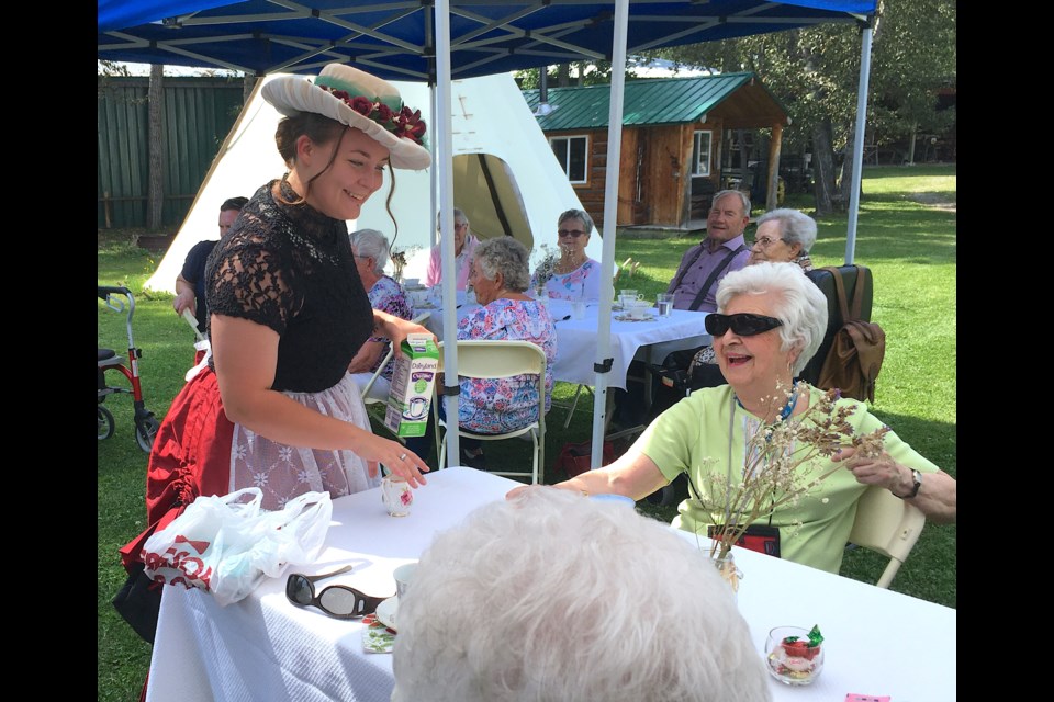 Donning a period costume, Aleecia Jessop, a summer student tour guide at the Sundre & District Museum, tends to the tables that were set up at the historic village grounds on Friday, Aug. 19 during a strawberry tea celebration of receiving from the Alberta Museums Association renewed recognized museum status. 
Simon Ducatel/MVP Staff