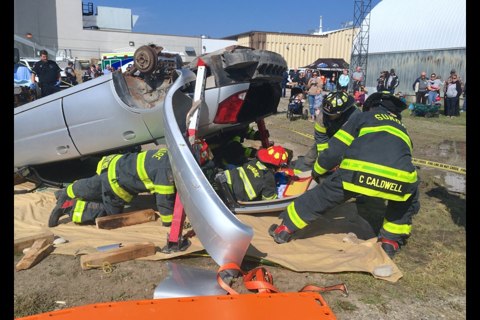 This year, members of the Sundre Fire Department demonstrated an emergency extrication from a staged single vehicle rollover scenario on Friday, Aug. 25 just outside the Sundre Arena during the annual Neighbour’s Day event organized by the Sundre Petroleum Operators Group. The mock exercise watched by dozens of people involved a driver who was intoxicated, a passenger who was ejected and declared deceased at the scene, as well as a surviving patient who sustained a severe spinal injury. Firefighters carefully pulled out the “injured” patient using as a temporary stretcher the vehicle’s roof section that was cut away using specialized tools. 
Simon Ducatel/MVP Staff