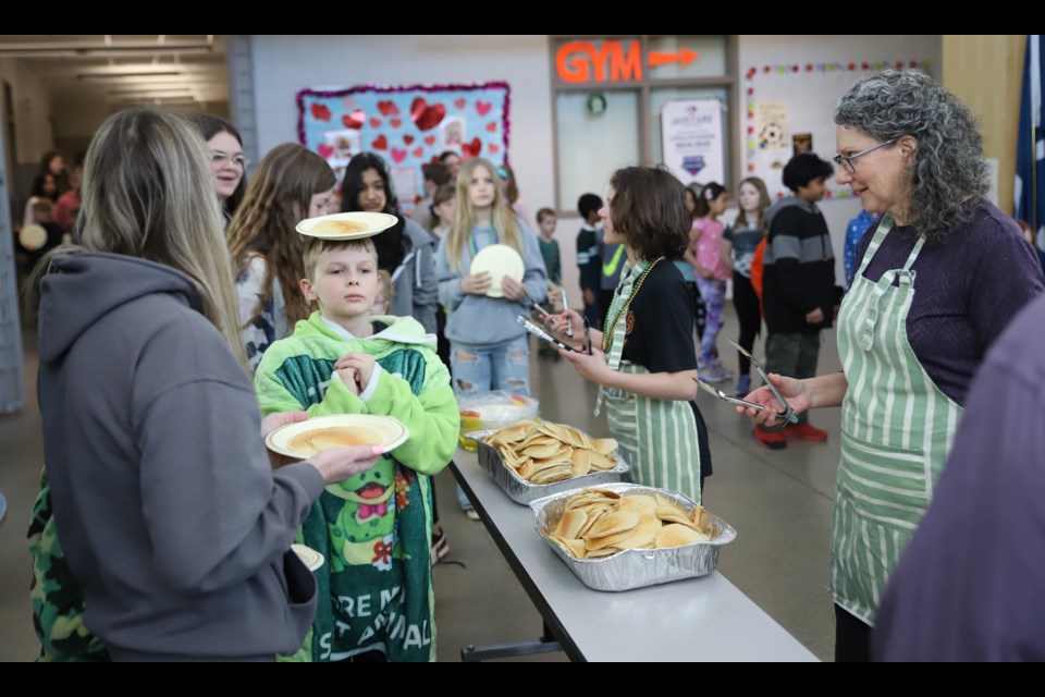 Aidric Dulmage brings his plate of pancakes forward ikn a perhaps unorthodox way as Sandra Boutwell of the Catholic Women's League waits to serve.
Doug Collie/MVP Staff