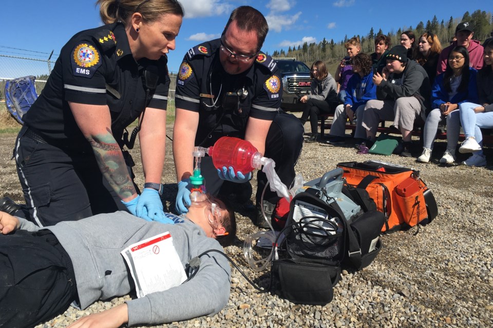 An EMS crew attempts cardiopulmonary resuscitation – commonly known as CPR – on Grade 11 student Riley Bashutski, the “patient” who was discovered motionless on the ground with no signs of life after being ejected at the scene of the staged crash while Sundre High School students get an up close and personal look as the mock situation unfolds on Tuesday, May 14 during the annual Prevent Alcohol and Risk-related Trauma in Youth (P.A.R.T.Y.) program. Simon Ducatel/MVP Staff