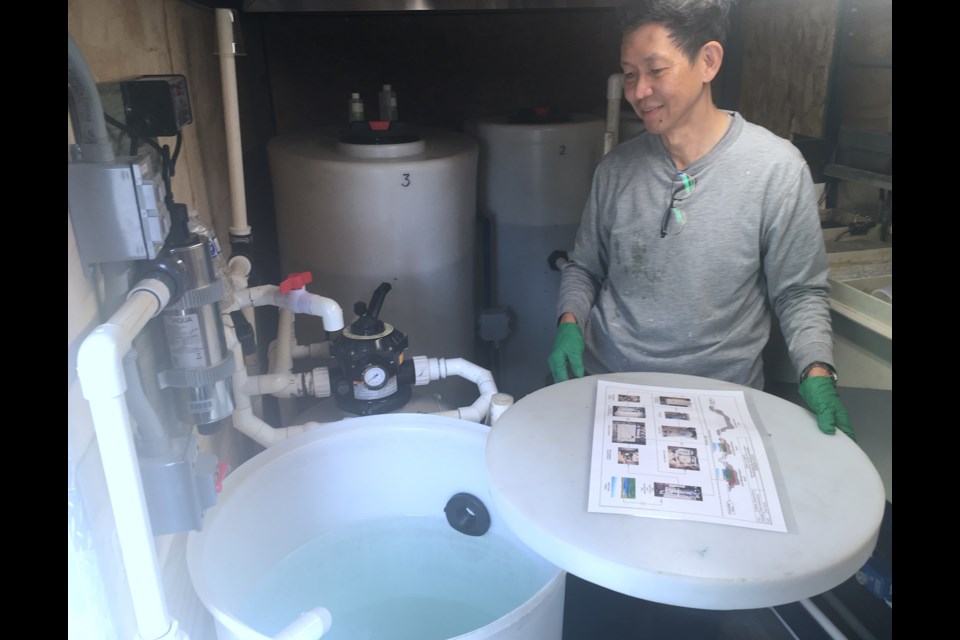 The scaled-down version of the pilot technology treats dozens of litres water, but the full-scale facility will process thousands of litres, said designer and developer Gonzales Lee, shown here demonstrating how clear the effluent ends up following the electro-flocculation process.  
Simon Ducatel/MVP Staff