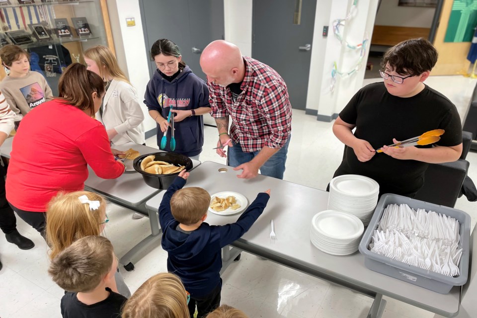 Stefan Labrecque, principal of Innisfail's St. Marguerite Bourgeoys Catholic School (centre), helps with the school's first-ever Thanksgiving Breakfast on Oct. 7. The special school project, driven by the Grade 7 leadership class, was created to raise awareness of the needs of the community and to provide Thanksgiving meals to Innisfail's less fortunate. Johnnie Bachusky/MVP Staff