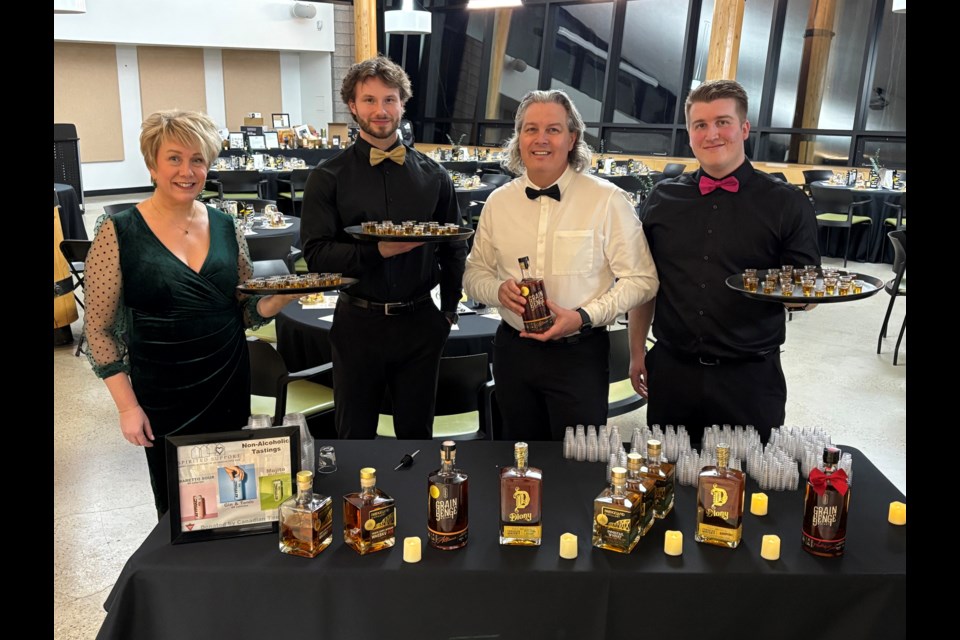 Members of The Blair Team – RE/MAX real estate central Alberta were eagerly ready to serve minutes prior to the arrival of a sell out audience of 102 ticket holders for the 2nd annual Spirited Support Whisky Tasting and Food Bank fundraiser on Jan. 31. From left to right are realtors Nicole Blair, Caleb Heinrichs, Darcy Blair and Ty Elliott. Johnnie Bachusky/MVP Staff