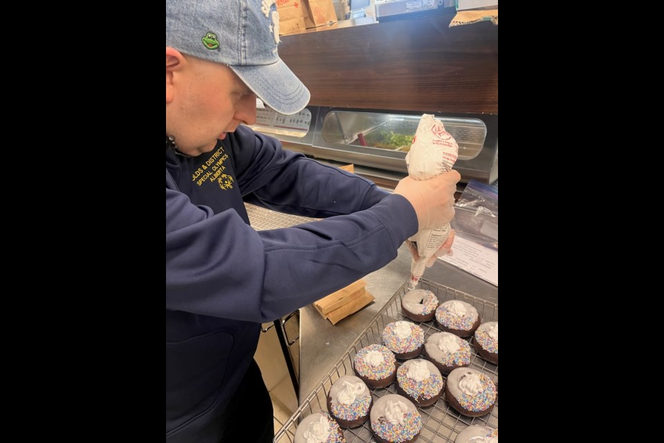 Evan Tippe applies the finishing touches to Tim Hortons Special Olympics donuts on behalf of of Olds & District Special Olympics.