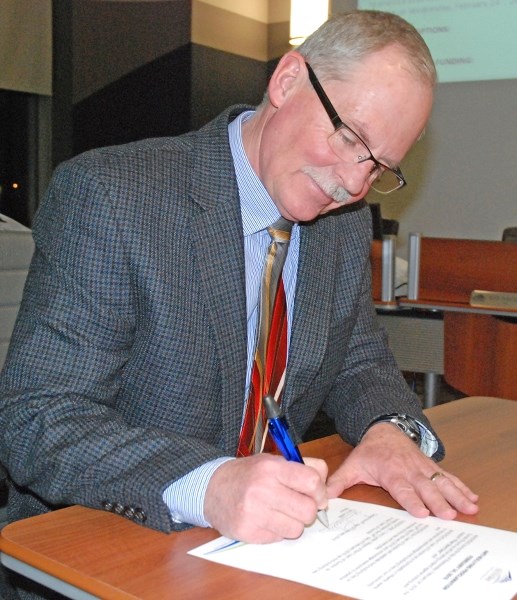 Town of Sundre mayor Terry Leslie signs a document during the Feb. 8 meeting proclaiming Wednesday, Feb. 24 as Anti-Bullying Day after council carried a motion to support the 