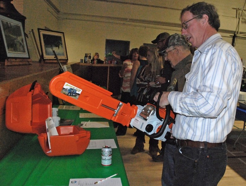 Bergen resident Les Free, who is a member of the Sundre Fish and Game Association, checks out a chainsaw that was among many items donated for the organization&#8217;s annual 