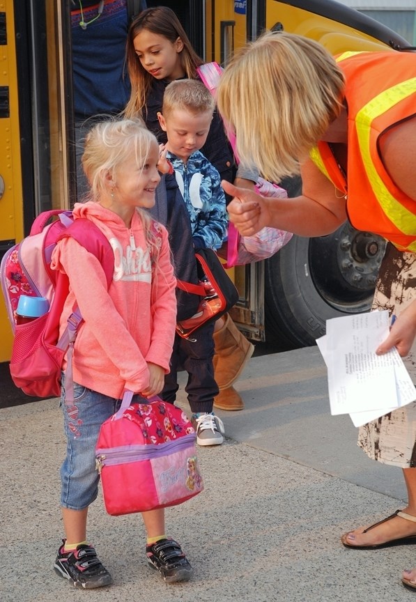 Grade 1 student Jillian Dumas is greeted Thursday morning by River Valley School staff member Karen Finley on the first day of classes. Motorists are reminded the school