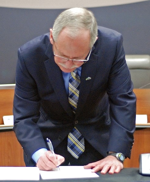 Mayor Terry Leslie signs official paperwork after reciting his oath of office on Oct. 23 during the new council&#8217;s organizational meeting, which started with a