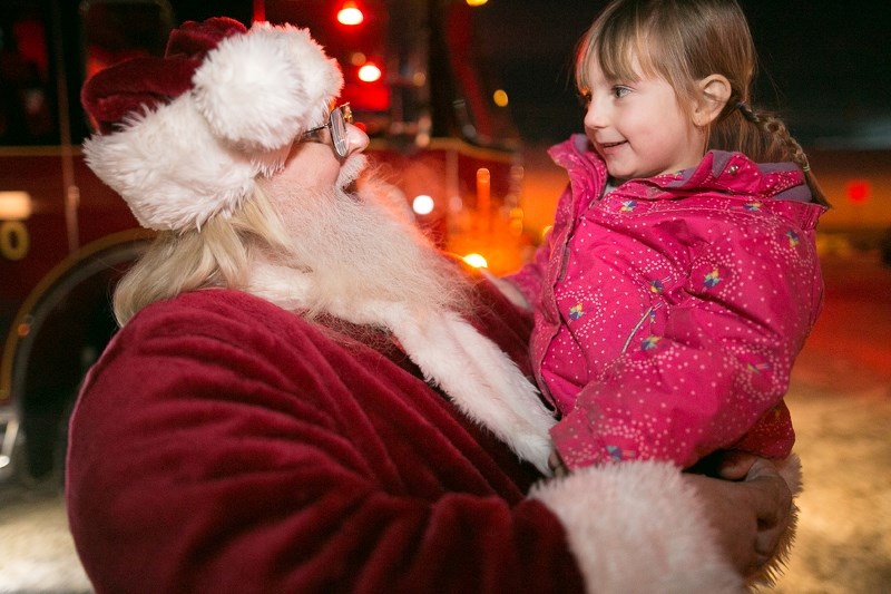 Santa Claus visits with Faith Pintea after arriving at the Sundre Community Centre in a fire truck during last year&#8217;s Sundown in Sundre.