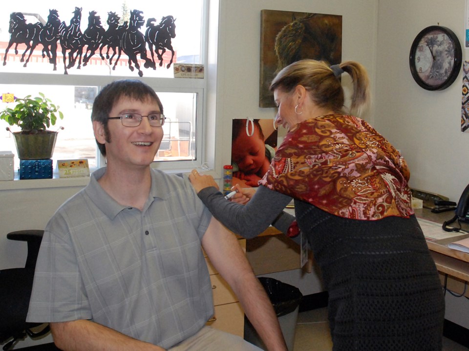 Simon Ducatel, editor of the Sundre Round Up, smiles in relief as Connie Sheppard, RN, finishes administering a flu shot at the Sundre Community Health Centre on Friday