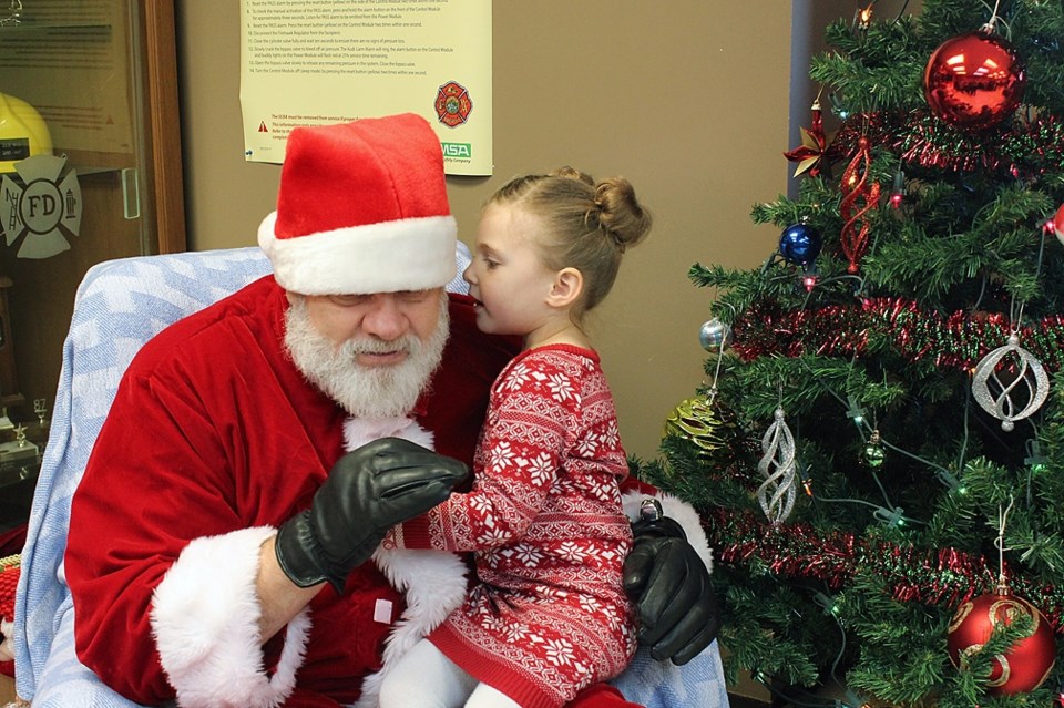 Santa listens carefully as four-year-old Sundre resident Devyn Prefontaine whispers her Christmas wish list into his ear. Before embarking on his worldwide gift-giving tour,