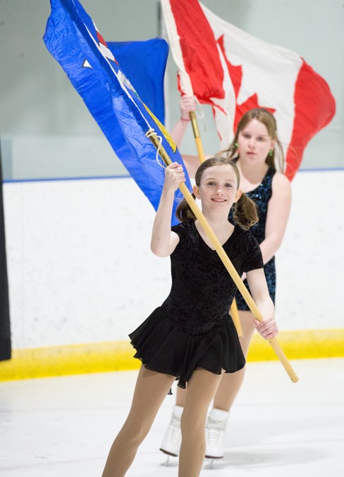  Carlee Clark, left, and Zoey Skage carry flags around the arena during the singing of O Canada at the start of the Sundre Skating Club's presentation of Barn Dance. Noel West/MVP Staff