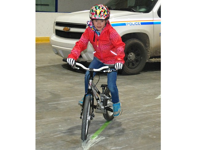  Dorothea Lee, 8, enthusiastically navigates around a figure eight course set up at the Sundre Arena last week as part of the Bike Rodeo.