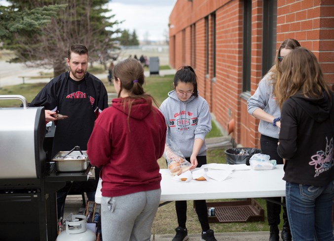  From left, vice principal Tyler Jesse, Davina Choi and Nora Wolfe serve up hamburgers during a barbecue at Sundre High School on May 8. The event was being held as a kickoff for the 50th annual May Queen fundraising event for the student union. Noel West/MVP Staff