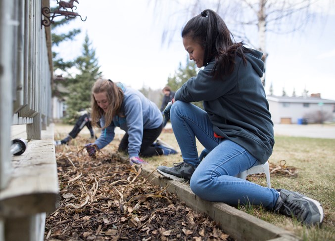 Grade 9 students Raegan Blatchford and Allyssa Bontilao clear a planting bed.