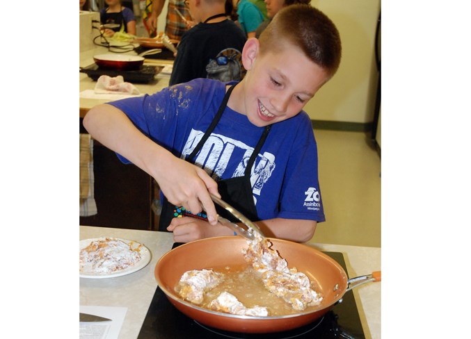  Eli Hill enthusiastically but cautiously fries up some Louisiana style chicken.