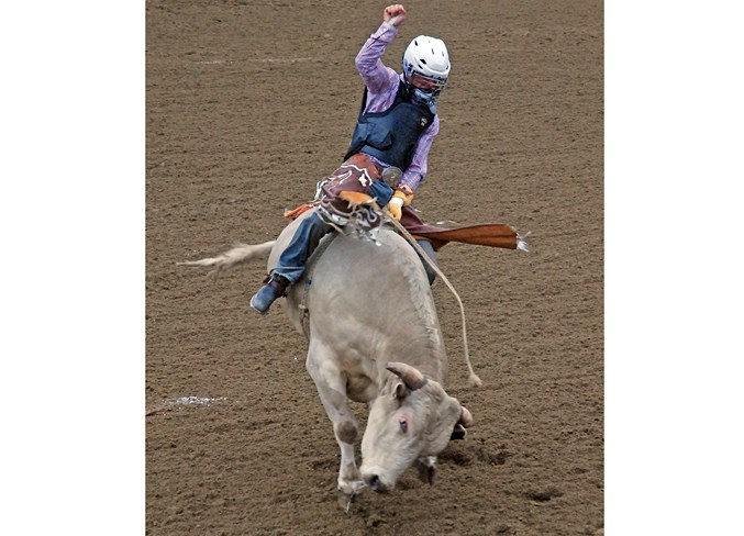  A bull rider manages to find a solid grip and hangs on through a rough ride.