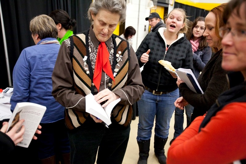 Temple Grandin signs a book while an excited fan sneaks a peak during a break in the conference at Olds College last Wednesday.