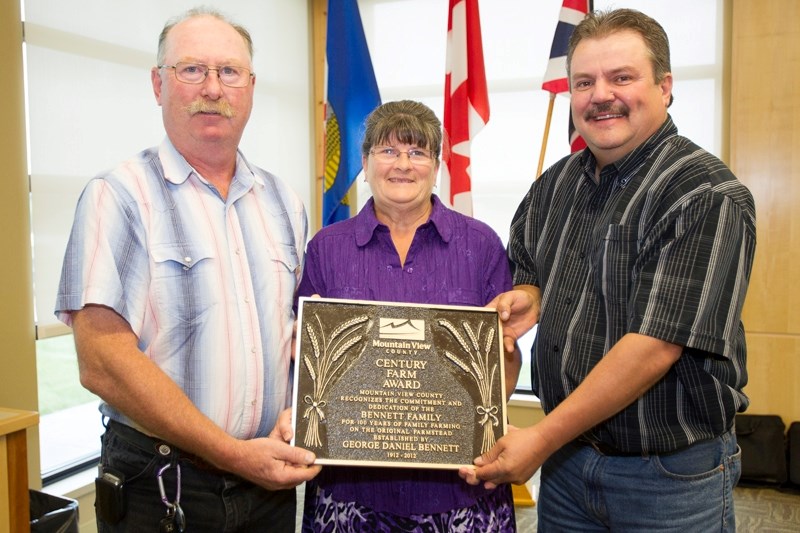 Thomas and Kathy Bennett receive their Century Farm Award from Mountain View County councillor Kevin Good during last Wednesday&#8217;s council meeting.