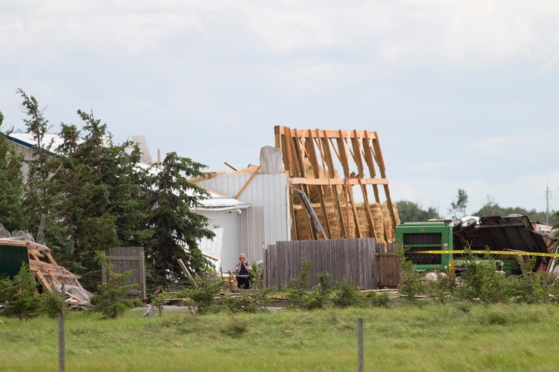 An RCMP member takes pictures of the damage to a property southwest of Didsbury after a severe storm passed through the area last Tuesday.