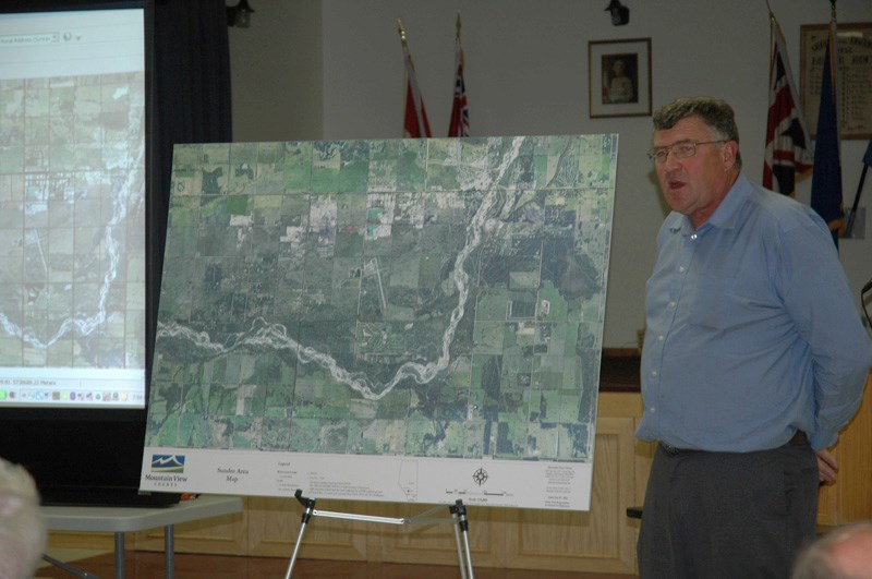 Councillor Paddy Munro shows guests a photo of the river upsteam of Sundre.