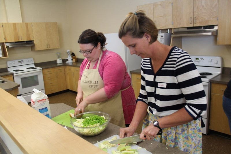 Jolene Sanford, left, and Krista Reinhardt chop vegetables as part of the Collective Kitchen Leader Training program at Didsbury High School.