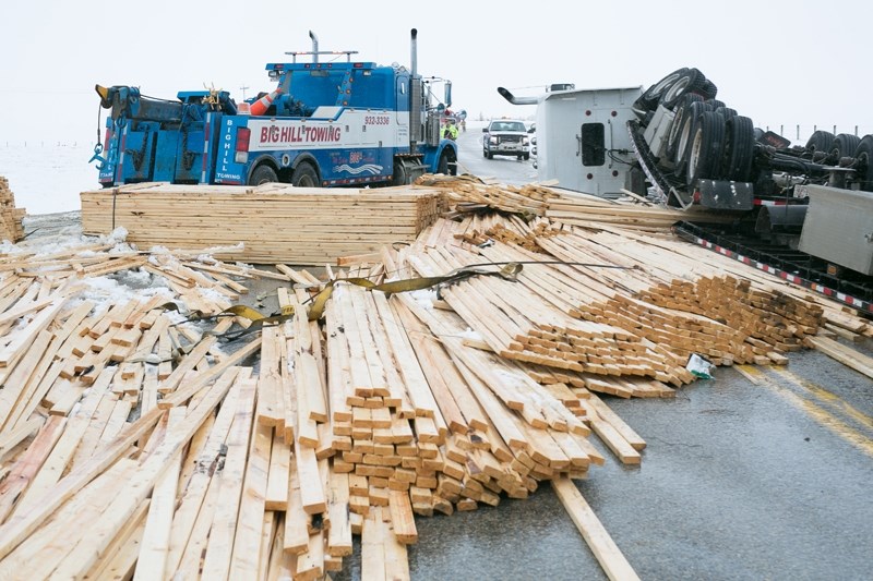 Crews clean up lumber and other debris following a rollover crash north of Cremona on Thursday.