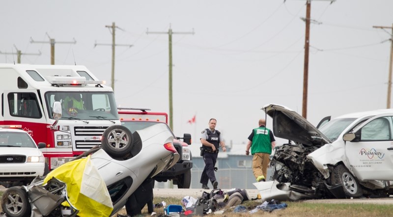 Emergency personnel work at the scene of a two-vehicle head-on collision that claimed two lives south of Carstairs on April 20. A third man was seriously injured in the