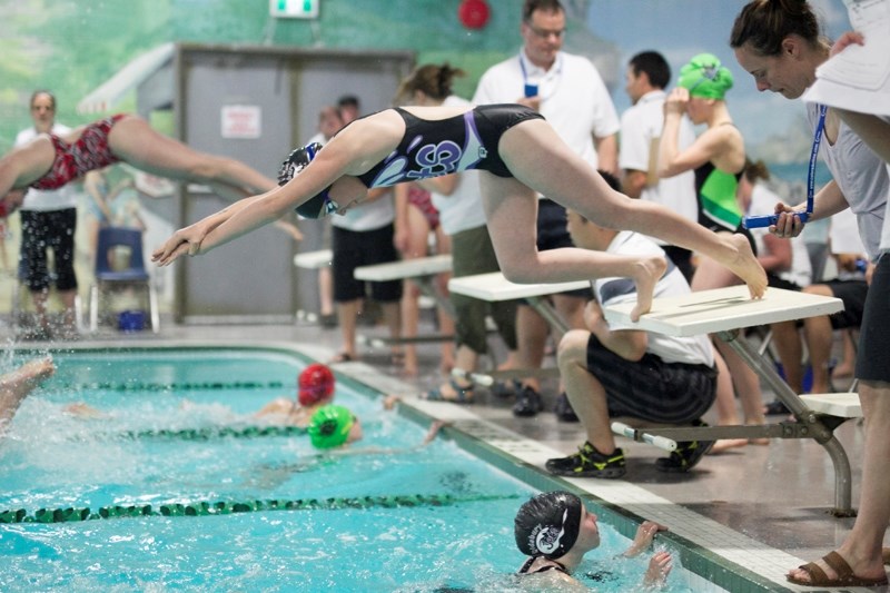 Leah Shantz of the Aqua Jets takes off from the blocks during a relay as teammate Lexi Jardine looks on from the pool.