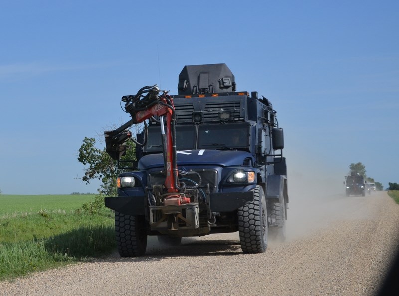 Tactical police vehicles leave a rural property east of Didsbury Thursday morning where a search warrant was being executed.