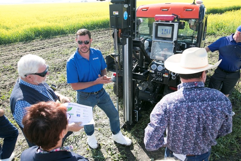 Mark Kuehn discusses high resolution soil information technology with a group of visitors in a field of canola at the Carlson farm east of Olds on July 13. The stop was part