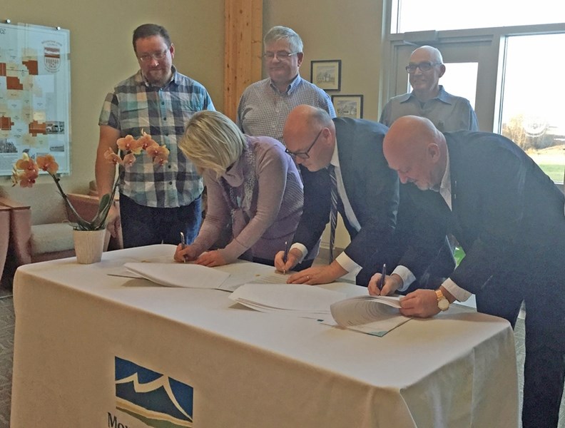 Tammy Mather, Legacy Land Trust Society executive director, left front row, county CAO Tony Martens, centre, and reeve Bruce Beattie, right, sign a conservation easement