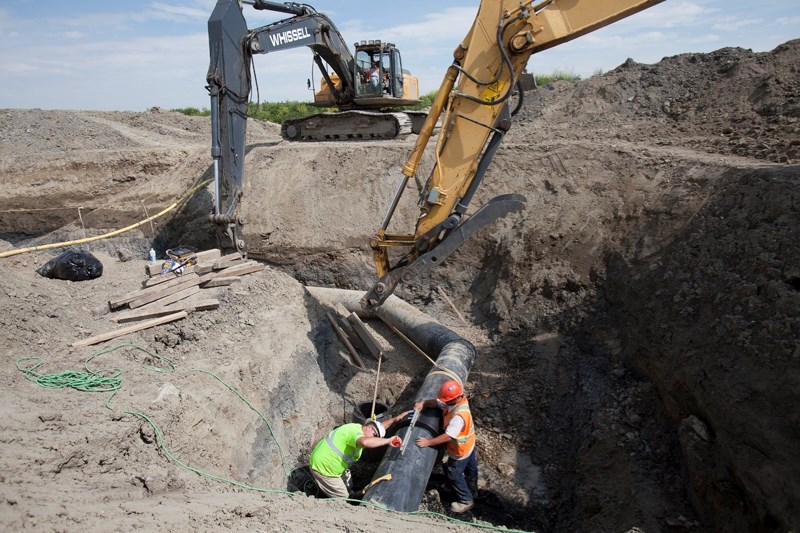 Workers fit a new electric fusion coupling on a section of the wastewater line just north of Olds on August 15.