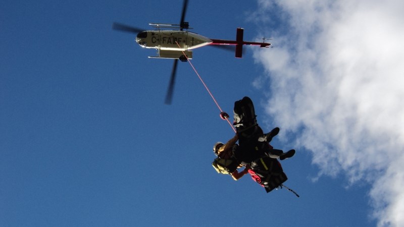 An injured man is slung out of an ATV crash scene west of Sundre.