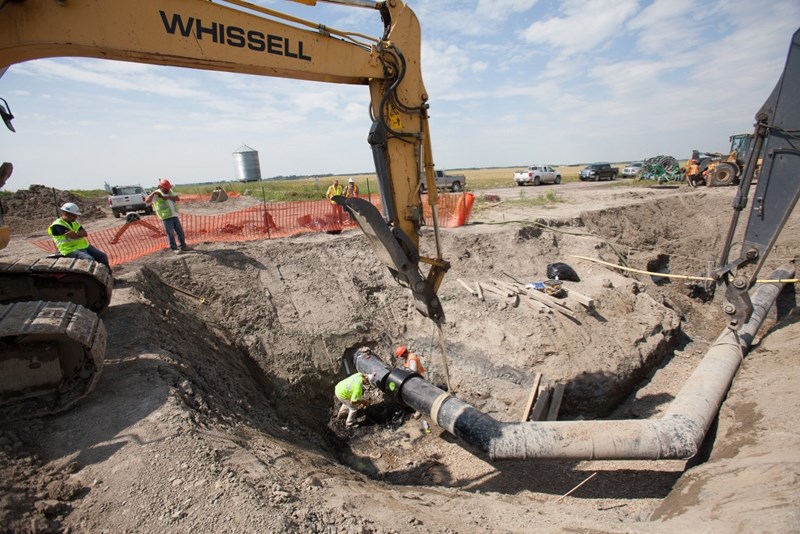 Workers position a new electric fusion coupling on a section of the wastewater line just north of Olds last summer.