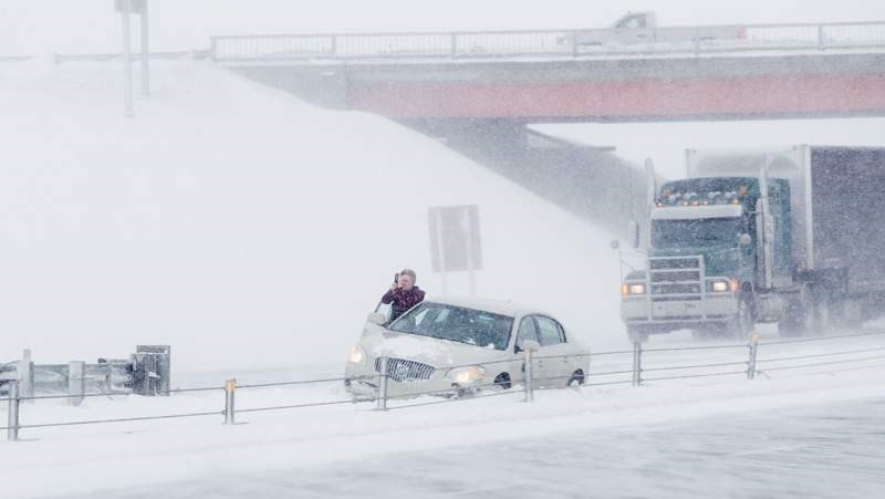 A motorist stands beside a vehicle in the northbound lane of Highway 2 near the Highway 27 overpass during a recent storm.