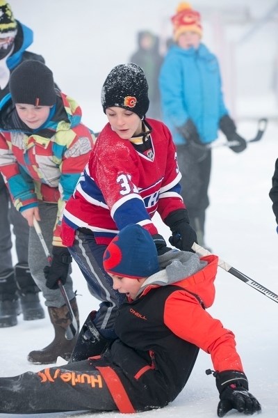 Deer Meadow School students Ben Nielsen (left), Sawyer Marshall (centre) and Connor Christiansen (on ground) brave -20 C temperatures while they play hockey outside the