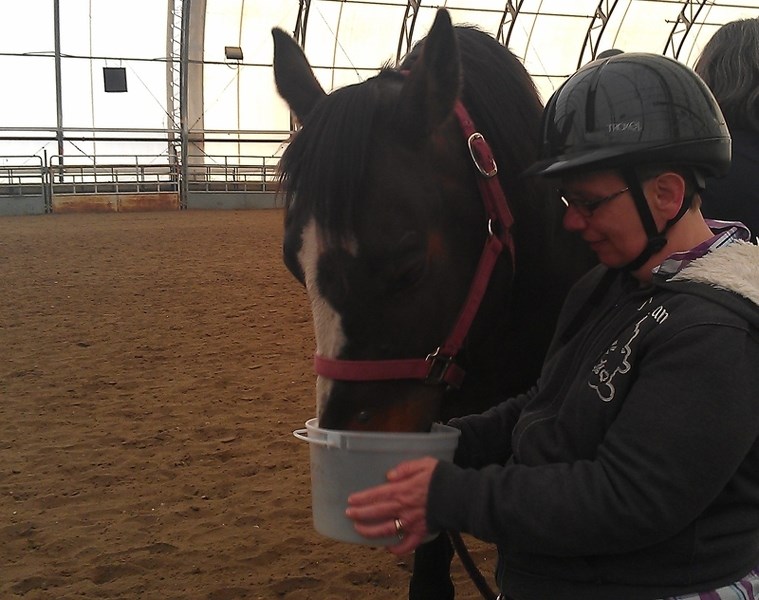 Bonnie Gooding feeds her horse at a Mount View Special Riding Association session at the Olds Regional Exhibition&#8217;s MegaDome.