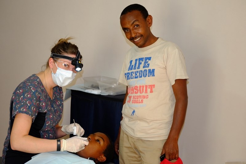 Lindsay Ord cleans the teeth of a girl. Ketemah (a driver and occasional translator) is standing by to help.