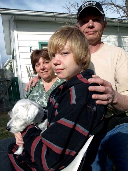 Taran Kovacs is flanked by his mother Tina, father Tom and puppy Zoey in the backyard of his Innisfail home. Taran has now returned to school after receiving his